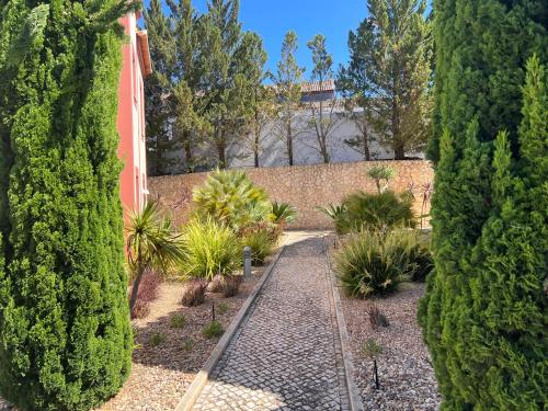 a garden with trees and plants and a stone wall at Vale da Pinta Golf in Estômbar