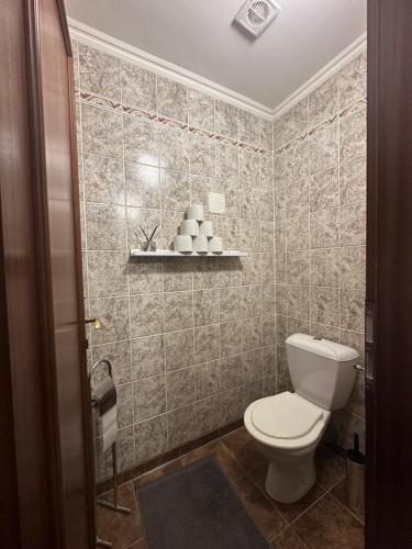 a bathroom with a toilet and a tiled wall at Apartment Reduta Celebration in Poprad