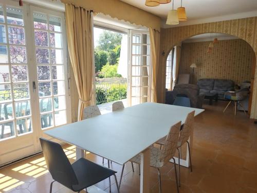 un salon avec une table et des chaises blanches dans l'établissement Grande maison vue sur mer, à Saint-Nazaire