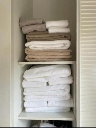 un placard avec une pile de serviettes blanches dans l'établissement Villa DUNE, à Biscarrosse