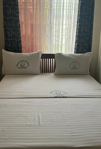 a bed with two pillows on it with a window at G & S Executive Lodge in Dar es Salaam