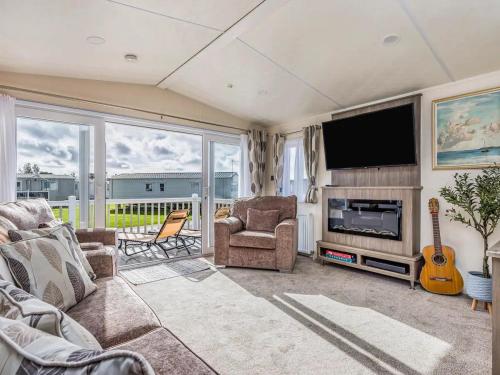 a living room with a couch and a tv and a guitar at Charming Chalet at Lakeside Park - Pass the Keys in Chichester