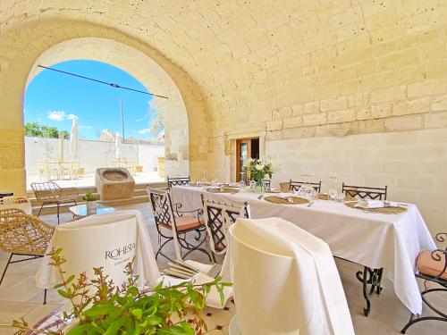 een eetkamer met witte tafels en stoelen en een boog bij Masseria La Millenaria in San Foca