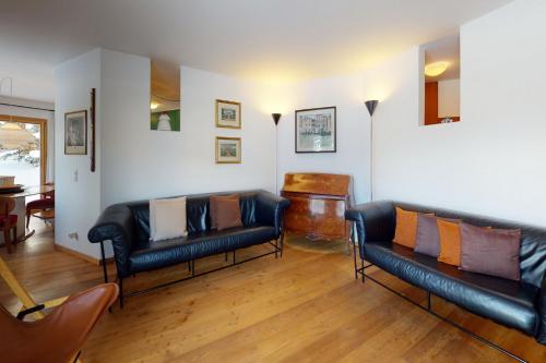 a living room with two leather couches and a piano at Apartment Cristolais in Samedan