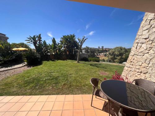 a patio with a table and chairs and a yard at Vale da Pinta Golf in Estômbar