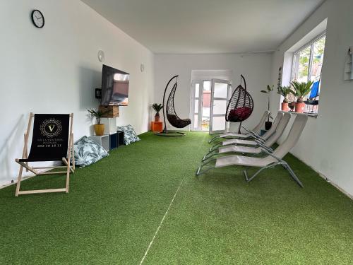 Habitación con alfombra verde, sillas y TV. en Villa Ventana 2 City Free Parking Śniadanie w cenie 503 18 18 11 en Poznan