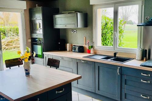 une cuisine avec des placards bleus et une table fleurie. dans l'établissement La Maraitière, à Guînes