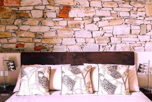 a bed with pillows in front of a stone wall at Tenuta Moncarlino in Morsasco