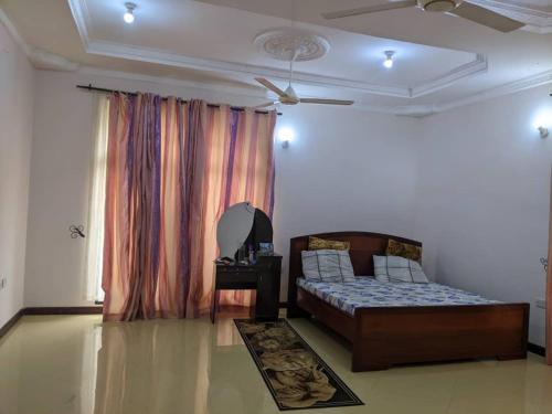 1 dormitorio con 1 cama y una ventana con cortinas en Mjengoni en Dar es Salaam
