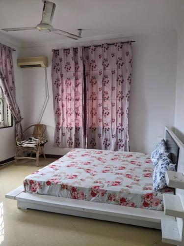 a bedroom with a bed and a window with pink curtains at Mjengoni in Dar es Salaam