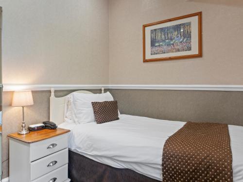 a hotel room with a bed and a table with a telephone at Higher Trapp Hotel in Padiham