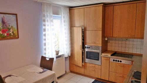 a kitchen with wooden cabinets and a table and a window at Ferienwohnung Eifelrose in Vorpochten