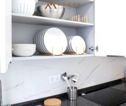 una cucina con piatti e utensili bianchi sugli scaffali di Apartamento Roncudo 4º planta a La Coruña