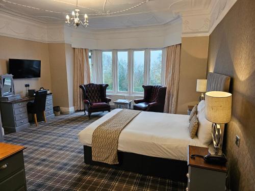 a hotel room with a bed and a desk and chairs at Higher Trapp Hotel in Padiham