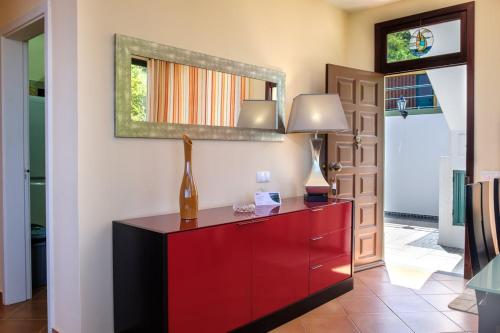 a red dresser with two lamps and a mirror at GuestReady - Hikers Haven in Faial