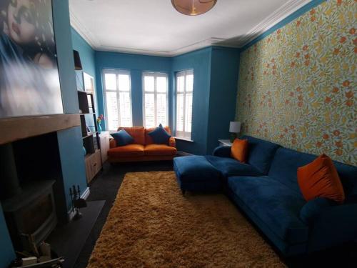 - un salon avec un canapé bleu et une chaise orange dans l'établissement Gorgeous Edwardian Terrace in Old Trafford, à Manchester