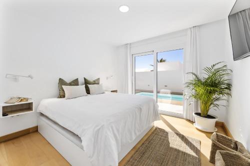 a white bedroom with a bed and a large window at Casa Beyel La Concha in Playa Honda