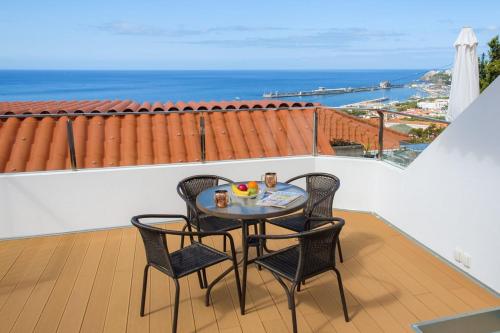 uma mesa e cadeiras numa varanda com vista para o oceano em GuestReady - An amazing blue ocean view em Funchal