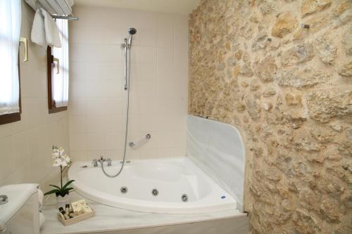 a bathroom with a bath tub and a stone wall at Hotel Palacio De La Viñona in Oviedo