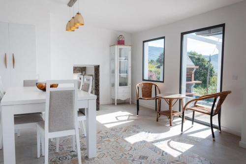 uma sala de jantar branca com uma mesa e cadeiras brancas em GuestReady - Quiet house & heated pool w sea view em Prazeres