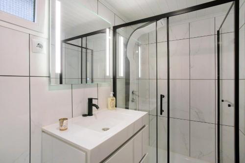 a white bathroom with a sink and a shower at Casa Estrela Do Norte in Ponta Delgada