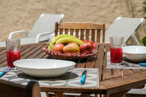 a wooden table with a bowl of fruit and bowls of apples at Windmill House- Near beach in Porto Santo