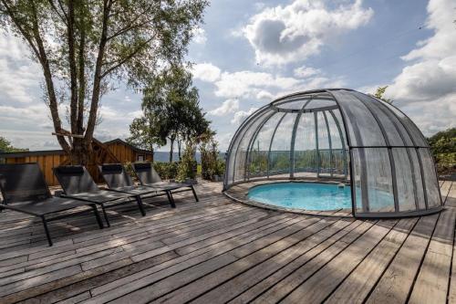 ein Glas-Iglu mit Stühlen und einem Pool auf einem Holzdeck in der Unterkunft Ferienhaus mit Privatpool für 4 Personen ca 120 m in Trois-Ponts, Wallonie Spa-Francorchamps und Umgebung in Trois-Ponts