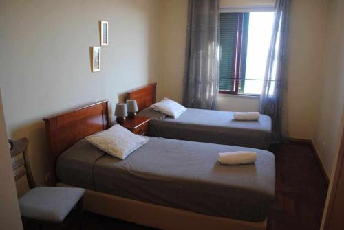 two beds in a small room with a window at Pia's Place - Apt with sea view in Caniço