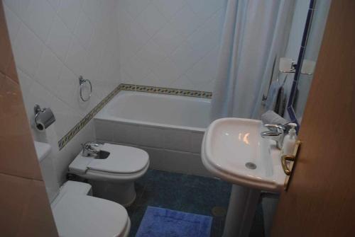 a bathroom with a toilet and a sink and a tub at Pia's Place - Apt with sea view in Caniço
