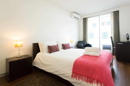 a bedroom with a large bed with a red blanket on it at Dolce Vita - City Center & Shopping Center in Funchal
