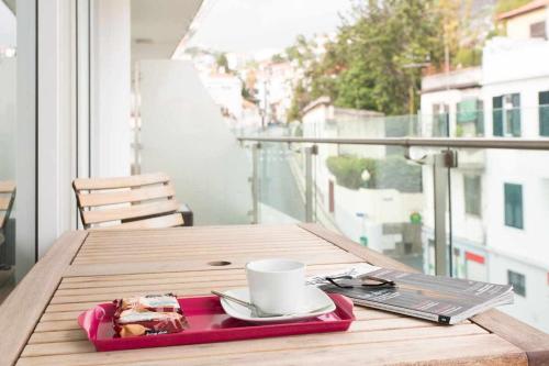 a tray with a coffee cup on a table on a balcony at Dolce Vita - City Center & Shopping Center in Funchal