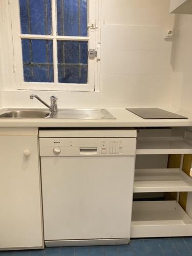 a kitchen with white cabinets and a sink and a window at Abesse 3 rooms Flat in Paris