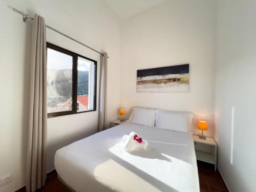 um quarto com uma cama branca e uma janela em GuestReady - Machico sea view residence - B em Machico