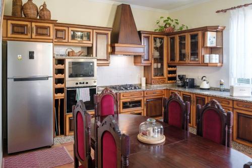 uma cozinha com armários de madeira, uma mesa e um frigorífico em GuestReady - Tranquil Spot in São Vicente em São Vicente