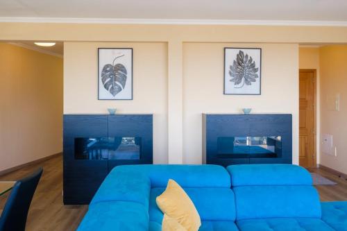 een blauwe bank in een woonkamer met foto's aan de muur bij GuestReady - One happy stay in Machico in Santa Cruz
