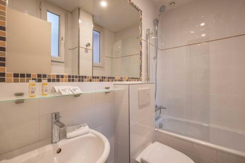 La salle de bains est pourvue d'une baignoire, d'un lavabo et d'un miroir. dans l'établissement Terminus Orléans Paris, à Paris