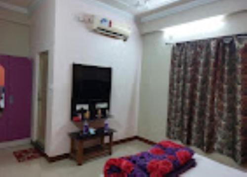 a living room with a bed and a flat screen tv at Hotel Royal Inn Tripura in Rādhākishorepur