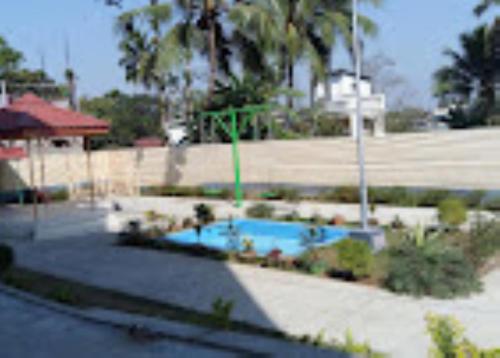 - une piscine dans un parc planté de palmiers dans l'établissement Hotel Royal Inn Tripura, à Rādhākishorepur