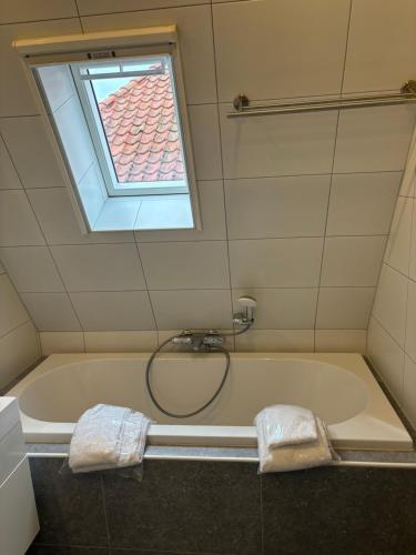a bathroom with a bath tub with a window at Appartementen De Helling 44 in Heeg