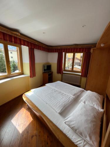 a large bed in a room with windows at goldenes kreuz in Vipiteno