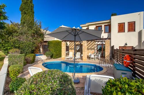 a house with a swimming pool with an umbrella at 2 bedroom Villa Kornos with private pool and golf views, Aphrodite Hills Resort in Kouklia