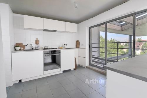eine Küche mit weißen Geräten und einem großen Fenster in der Unterkunft LA SERENITE in Colombes