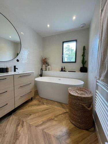 La salle de bains est pourvue d'une grande baignoire blanche et d'un miroir. dans l'établissement VILLA avec piscine aux portes d’Uzès, à Saint-Siffret