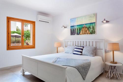 ein Schlafzimmer mit einem weißen Bett und einem Fenster in der Unterkunft Villa Torre Mar with swimming pool and 100m to the beach in Cala Santanyi