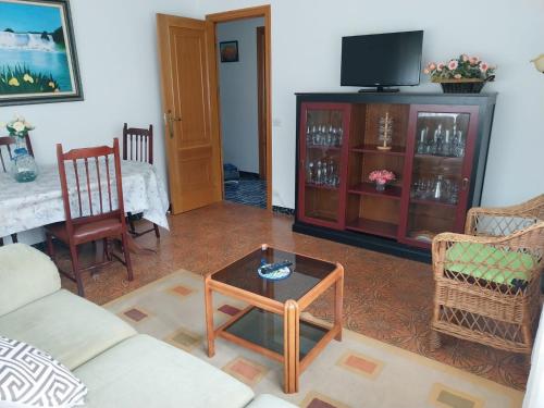 sala de estar con sofá, mesa y TV en Casa Vista Alegre en Oia, en Oia