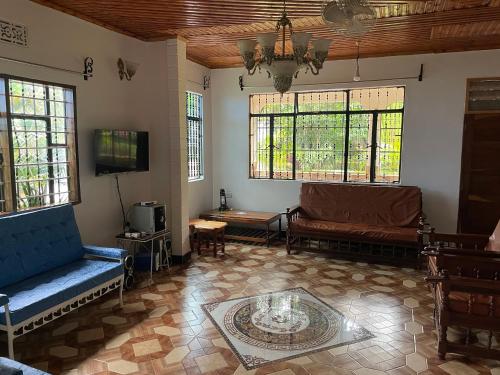 salon z kanapami, telewizorem i oknami w obiekcie Kilimanjaro Ultimate Home Stay w mieście Moshi