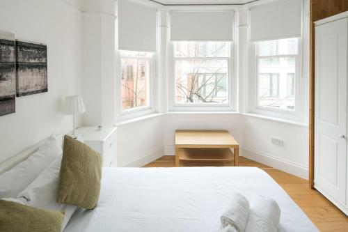 Elegant 1BR Apartment Near Central London في لندن: غرفة نوم بيضاء بها سرير ونوافذ