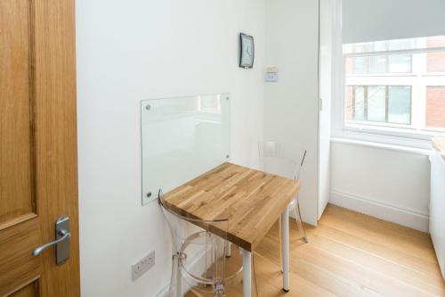 a small kitchen with a wooden table and a refrigerator at Elegant 1BR Apartment Near Central London in London