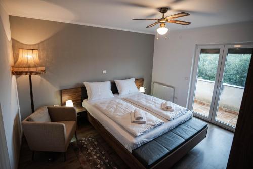 a bedroom with a bed and a chair and a window at Olive Garden Apartment in Plovanija