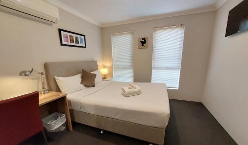 a small bedroom with a bed and a desk and window at Ellard Bed & Breakfast in Perth